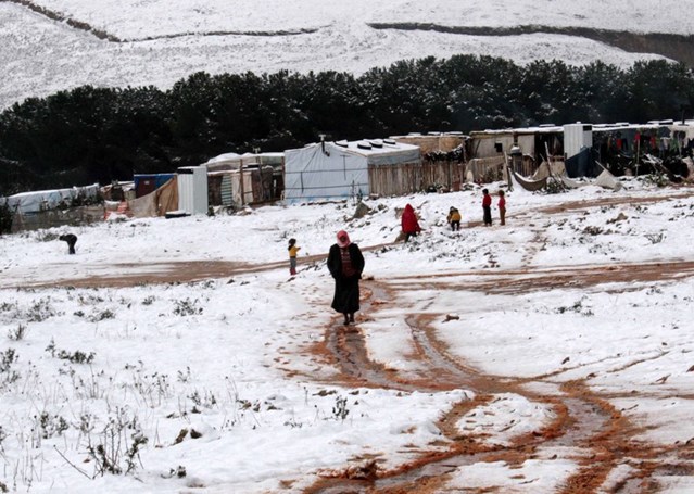 A woman walks through the snow in a Syrian refugee camp in Marj al-Khawkh, southern Lebanon, 9 January 2015. © AFP/Getty Images