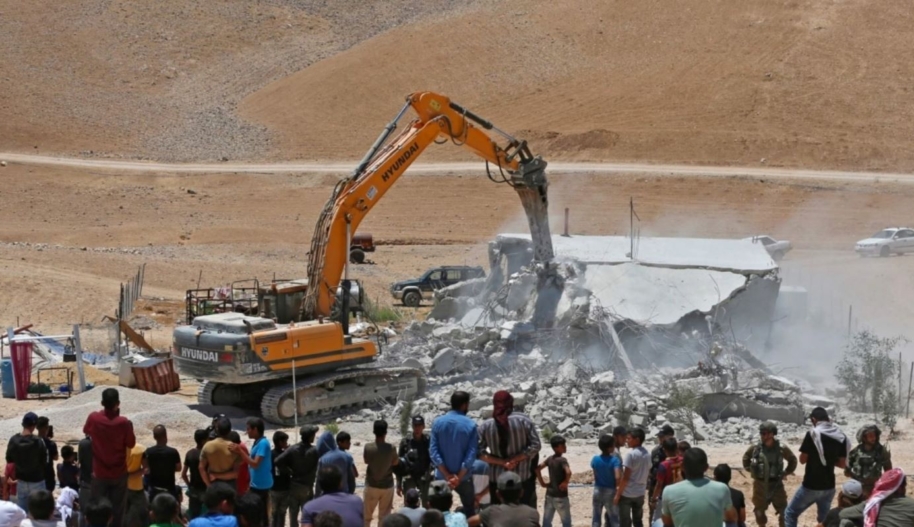 Residents watch as an Israeli bulldozer demolishes a Palestinian house in the Umm Qasas area of Masafer Yatta in the occupied West Bank on July 25, 2022. (Photo by MOSAB SHAWER / AFP) (Photo by MOSAB SHAWER/AFP via Getty Images)