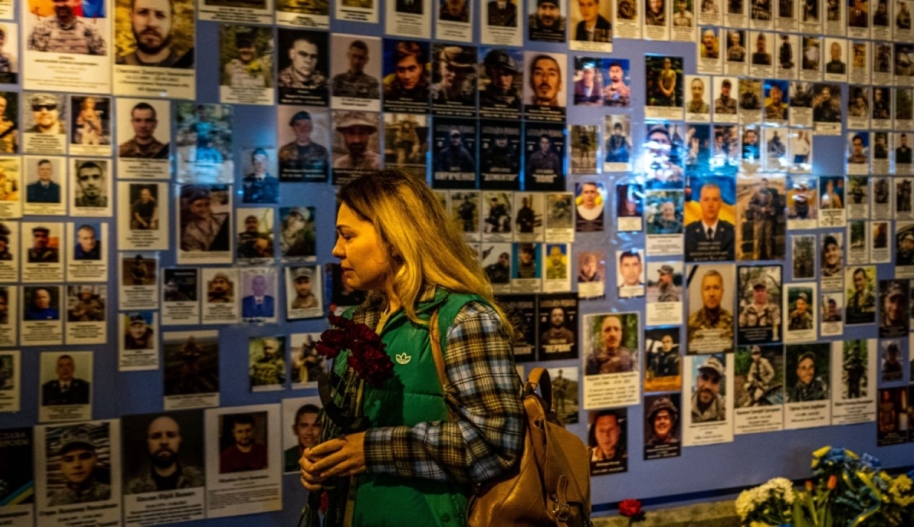 A woman reacts in front of pictures displayed at a Memory Wall of Fallen Defenders of Ukraine during the Russian invasion of Ukraine in Kyiv on February 24, 2023 on the first anniversary of the war. Photo by DIMITAR DILKOFF/AFP via Getty Images.