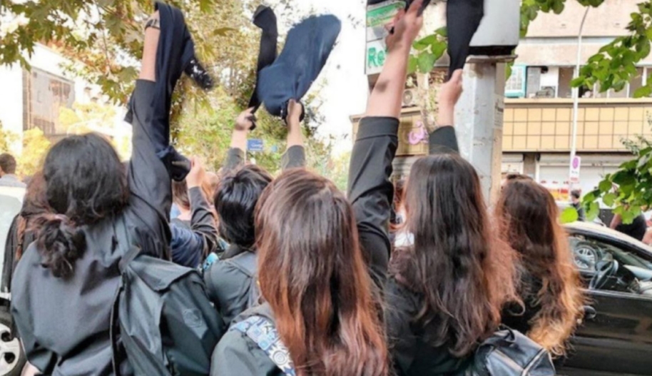 Iranian female students pictured from the back with their hair uncovered and raising their compulsory veils in the air. © private