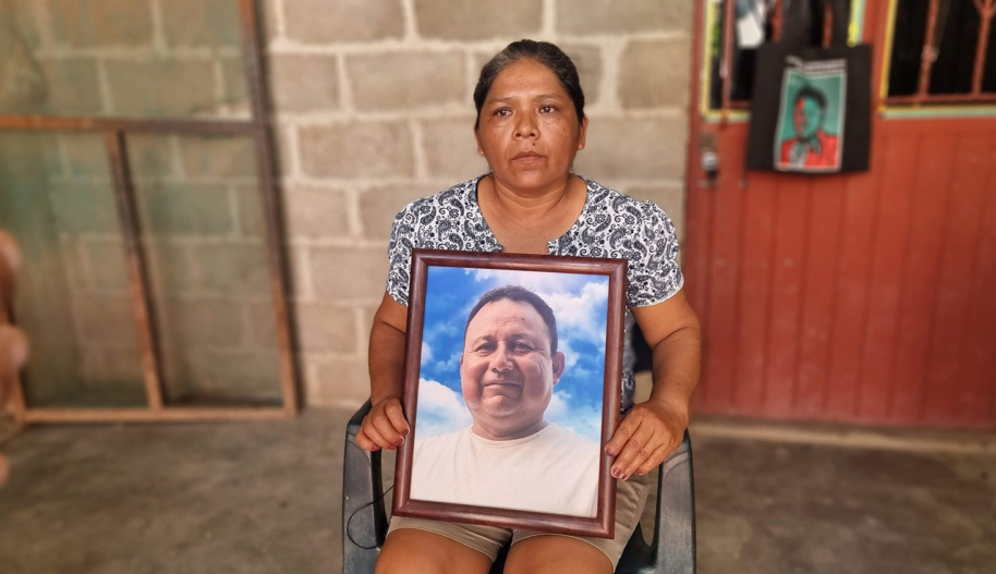 A woman sitting in a chair holds a portrait of her late husband, a Mexican journalist who was assassinated for his reporting.